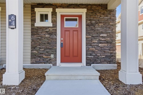 Entryway featuring a red paneled door with glass insert, stacked stone facade, horizontal siding, and a concrete porch with steps - 64 17832 78 Street, Edmonton, AB - Outdoor