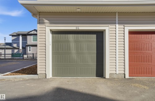 Individual garage with a sage green paneled door, light beige siding, white trim, and a concrete apron - 64 17832 78 Street, Edmonton, AB - Outdoor With Exterior