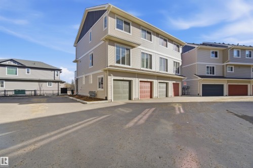 Three-story townhome with light-toned horizontal siding and dark trim accents - 64 17832 78 Street, Edmonton, AB - Outdoor