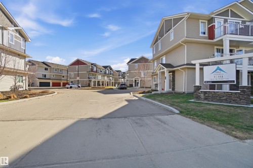 Modern multi-story residential buildings featuring mixed siding, balconies with glass railings, and a stone-clad entry sign - 64 17832 78 Street, Edmonton, AB - Outdoor With Balcony With Facade