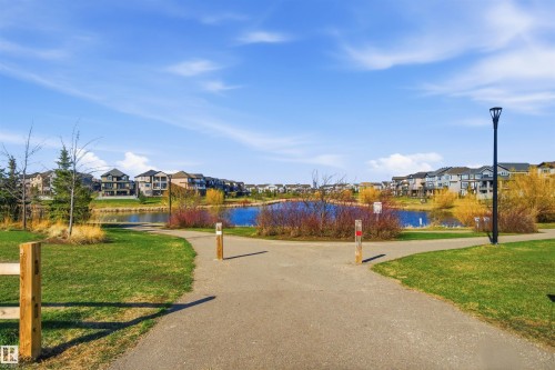 Paved pathways bordering a substantial body of water, surrounded by green spaces and residential properties - 64 17832 78 Street, Edmonton, AB - Outdoor With View