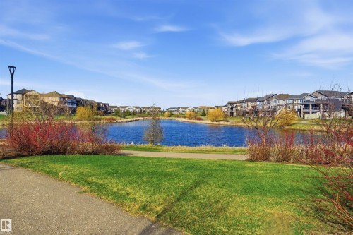 Waterside homes featuring varied architectural styles and private balconies, bordering a paved pathway and green space - 64 17832 78 Street, Edmonton, AB - Outdoor With Body Of Water With View