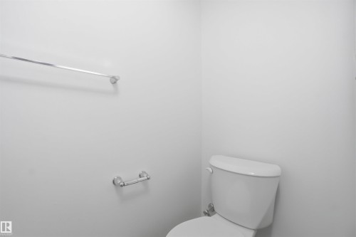 White toilet with visible plumbing, chrome towel bar, and toilet paper holder - 64 17832 78 Street, Edmonton, AB - Indoor Photo Showing Bathroom