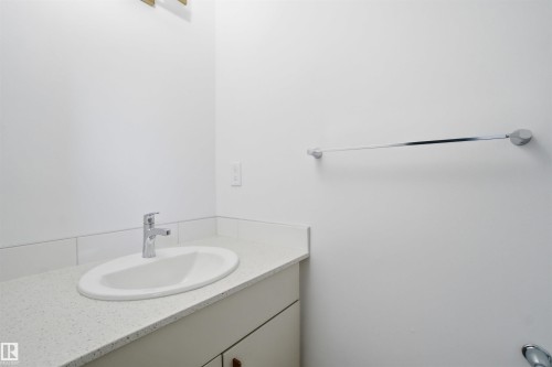 Bathroom vanity featuring an oval undermount sink, a chrome single-handle faucet, and a light-toned speckled countertop - 64 17832 78 Street, Edmonton, AB - Indoor Photo Showing Bathroom