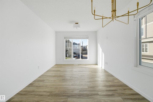 Room featuring wood-finish flooring, white walls, and a modern brass chandelier - 64 17832 78 Street, Edmonton, AB - Indoor Photo Showing Other Room