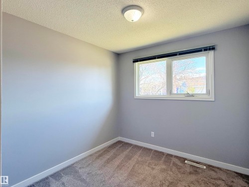 Bright room featuring a double-pane window with blinds, light gray walls, and textured carpeting - 3912 108 Street, Edmonton, AB - Indoor Photo Showing Other Room