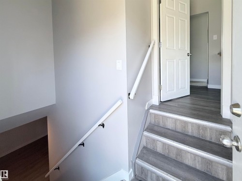 Side entrance, Staircase featuring wood-finish treads, risers, and handrails with matte black brackets - 3912 108 Street, Edmonton, AB - Indoor Photo Showing Other Room