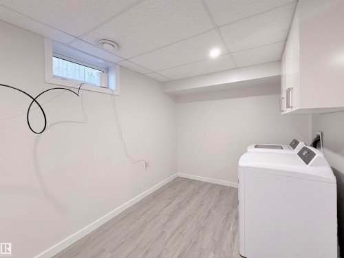 Dedicated laundry area featuring a drop ceiling with recessed lighting, light wood-finish flooring, white baseboards, and a window for natural light - 3912 108 Street, Edmonton, AB - Indoor Photo Showing Laundry Room