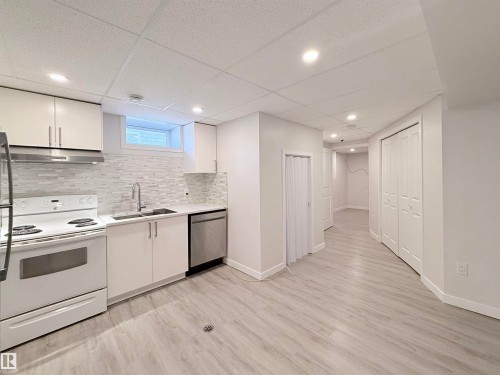 Open-concept kitchen with white cabinetry, stainless steel dishwasher, and a tile backsplash - 3912 108 Street, Edmonton, AB - Indoor Photo Showing Kitchen