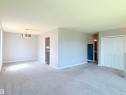 Spacious interior featuring light gray carpeting, white baseboards, and a contemporary ceiling light fixture - 3912 108 Street, Edmonton, AB  - Indoor 