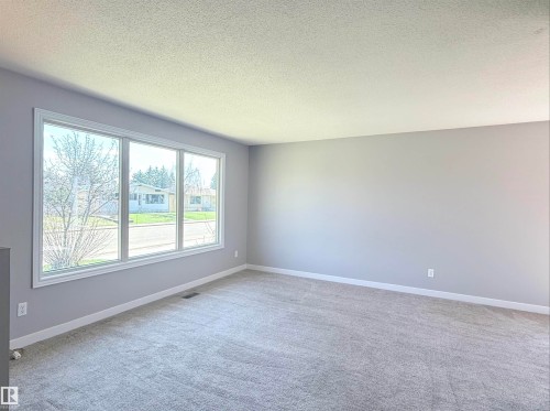 Spacious room featuring light gray walls, plush gray carpeting, and a large bay window with white trim - 3912 108 Street, Edmonton, AB - Indoor Photo Showing Other Room