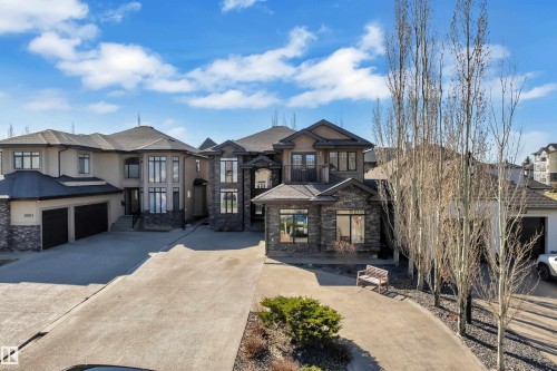 Contemporary residence featuring a multi-tone stucco and stone facade, multiple large windows, a prominent two-car garage, and a concrete driveway - 10915 175 Avenue, Edmonton, AB - Outdoor With Facade