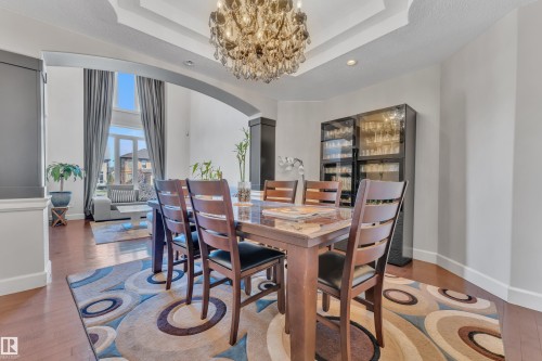 Dining area featuring a crystal chandelier, tray ceiling, and wood-finish flooring - 10915 175 Avenue, Edmonton, AB - Indoor Photo Showing Dining Room