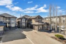 Contemporary exterior featuring a stone facade, multiple large windows, an attached two-car garage, an additional single-car garage, and a concrete driveway - 10915 175 Avenue, Edmonton, AB  - Outdoor With Facade 