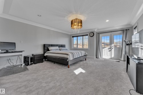 Spacious bedroom with light gray carpeting, crown molding, and a decorative ceiling fixture - 10915 175 Avenue, Edmonton, AB - Indoor Photo Showing Bedroom