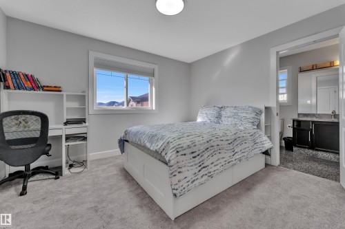 Bedroom featuring light gray walls, gray carpeting, a large window with white trim, and direct access to a bathroom - 10915 175 Avenue, Edmonton, AB - Indoor Photo Showing Bedroom