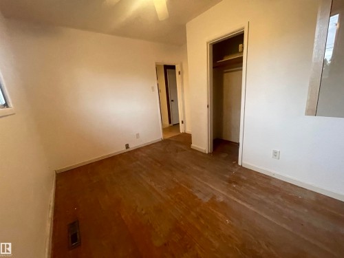 Room featuring wood-finish flooring, white walls, a window, and a built-in closet with shelving - 13804 132 Avenue, Edmonton, AB - Indoor Photo Showing Other Room