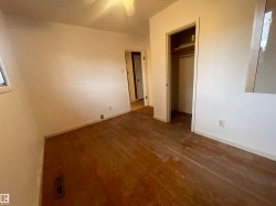 Room featuring wood-finish flooring, white walls, a window, and a built-in closet with shelving - 