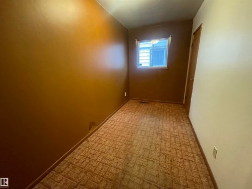 Room featuring patterned carpet, a single window with white trim, and a wood-panel door - 13804 132 Avenue, Edmonton, AB - Indoor Photo Showing Other Room