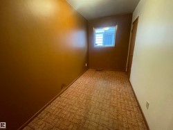 Room featuring patterned carpet, a single window with white trim, and a wood-panel door - 