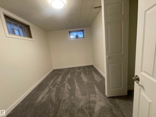 Room featuring new grey patterned carpeting, white walls, two egress windows, a flush-mount ceiling light, and white trim throughout - 13804 132 Avenue, Edmonton, AB - Indoor Photo Showing Other Room