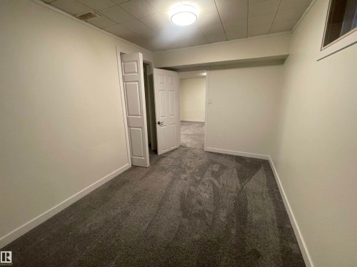 Interior room featuring neutral wall paint, gray patterned carpet, a white paneled door, a flush-mount ceiling light, and white baseboards - 13804 132 Avenue, Edmonton, AB - Indoor Photo Showing Other Room