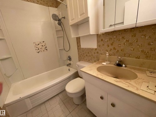 Bathroom featuring a white bathtub, shower with built-in shelving, vanity with integrated sink, and upper cabinetry with mirrored medicine cabinet - 13804 132 Avenue, Edmonton, AB - Indoor Photo Showing Bathroom