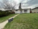 White siding exterior with a prominent bay window, front entrance with steps, concrete walkway, and a landscaped front yard with grass and mature shrubbery - 13804 132 Avenue, Edmonton, AB  - Outdoor 