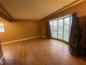 Expansive interior space featuring wood-finish flooring, a tray ceiling, and a large bay window - 13804 132 Avenue, Edmonton, AB  - Indoor Photo Showing Other Room 