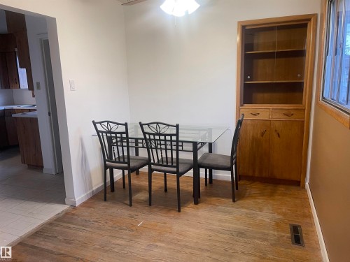 Dining area featuring wood-finish flooring and a built-in wooden hutch with glass-fronted shelving - 13804 132 Avenue, Edmonton, AB - Indoor Photo Showing Dining Room