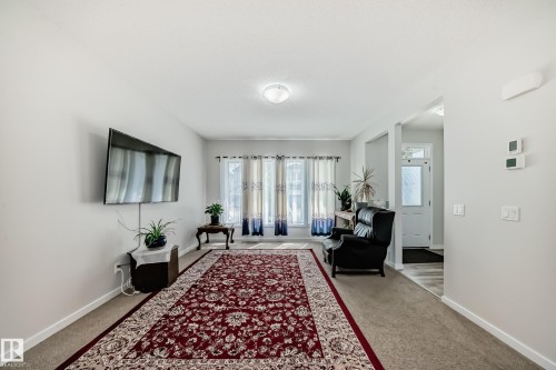 Bright living space featuring neutral wall tones, recessed lighting, and a front entry door with privacy glass - 4609 Alwood Way, Edmonton, AB - Indoor