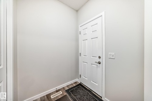 White paneled door with brushed nickel hardware, light gray walls, wood-finish flooring, and white baseboards - 4609 Alwood Way, Edmonton, AB - Indoor Photo Showing Other Room