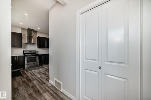 Kitchen entry with wood-finish flooring, dark cabinetry, stainless steel appliances, and a tile backsplash - 4609 Alwood Way, Edmonton, AB - Indoor