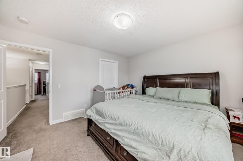 Carpeted bedroom featuring a dark wood bed frame, white walls, and a round flush-mount ceiling light - 4609 Alwood Way, Edmonton, AB - Indoor Photo Showing Bedroom