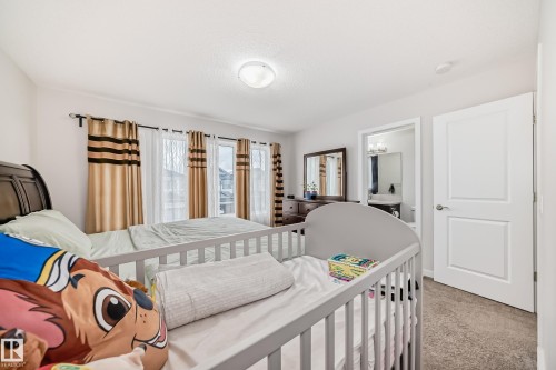 Carpeted room with white walls, featuring a private bathroom entry and large windows - 4609 Alwood Way, Edmonton, AB - Indoor Photo Showing Bedroom