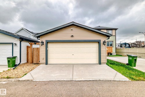 Detached garage with a single overhead door, light beige siding, and dark trim - 4609 Alwood Way, Edmonton, AB - Outdoor With Exterior