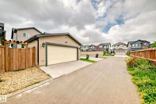 Detached garage with beige siding and dark trim, featuring an exterior light fixture and a concrete driveway - 4609 Alwood Way, Edmonton, AB - Outdoor