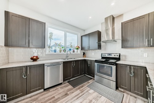 Modern kitchen featuring wood-finish flooring and dark wood-finish cabinetry - 4609 Alwood Way, Edmonton, AB - Indoor Photo Showing Kitchen With Stainless Steel Kitchen With Double Sink With Upgraded Kitchen