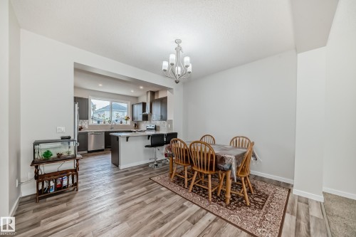 Open-concept dining area featuring wood-finish flooring, a chandelier lighting fixture, and a pass-through to the kitchen - 4609 Alwood Way, Edmonton, AB - Indoor Photo Showing Dining Room