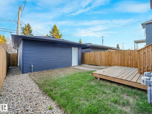 Detached garage with horizontal siding, a wooden privacy fence, a ground-level wooden deck, and a gravel walkway - 15731 109 Avenue, Edmonton, AB - Outdoor