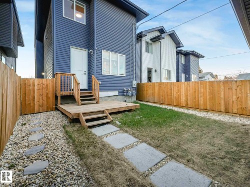 Rear exterior featuring blue horizontal siding, a wooden deck with steps, and a white entry door - 15731 109 Avenue, Edmonton, AB - Outdoor With Exterior