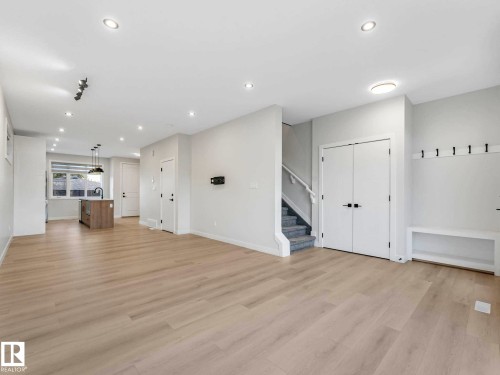 Spacious open-concept room featuring light wood-finish flooring, recessed ceiling lighting, and a built-in coat rack with shelving - 15731 109 Avenue, Edmonton, AB - Indoor