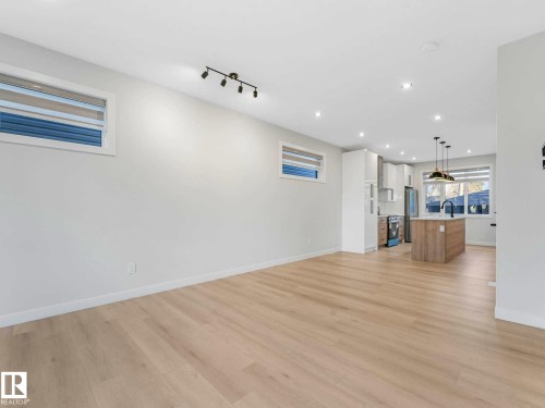 Open-concept living space featuring wood-finish flooring, recessed lighting, and a modern kitchen - 15731 109 Avenue, Edmonton, AB - Indoor