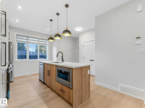 Kitchen island with integrated microwave, undermount sink, and matte black faucet - 15731 109 Avenue, Edmonton, AB - Indoor Photo Showing Kitchen With Upgraded Kitchen