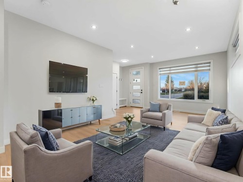 Bright living area featuring light wood-finish flooring, recessed lighting, a large picture window, and a modern entryway door with frosted glass panels - 15731 109 Avenue, Edmonton, AB - Indoor Photo Showing Living Room