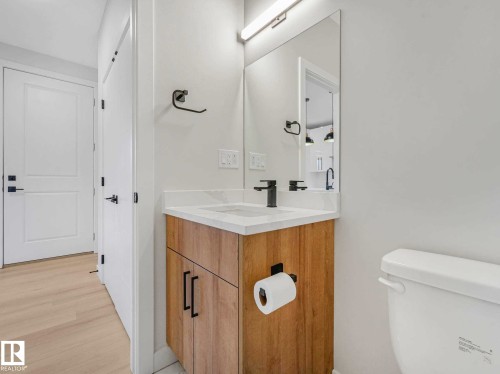 Modern bathroom featuring a wood-finish vanity with a white countertop and integrated sink - 15731 109 Avenue, Edmonton, AB - Indoor Photo Showing Bathroom