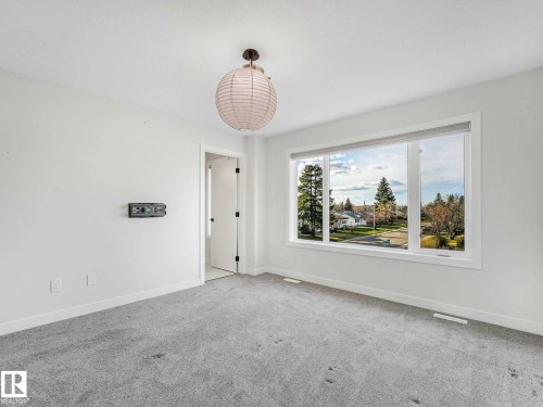 Bright interior space featuring a large picture window, light grey carpeting, white painted walls, and a recessed ceiling light fixture - 15731 109 Avenue, Edmonton, AB - Indoor