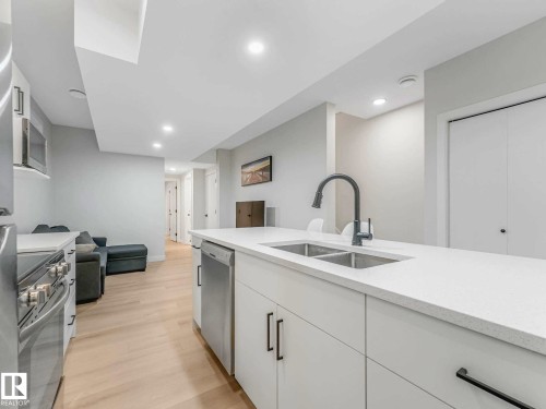 Spacious kitchen island featuring a dual basin sink and a contemporary gooseneck faucet - 15731 109 Avenue, Edmonton, AB - Indoor Photo Showing Kitchen With Double Sink