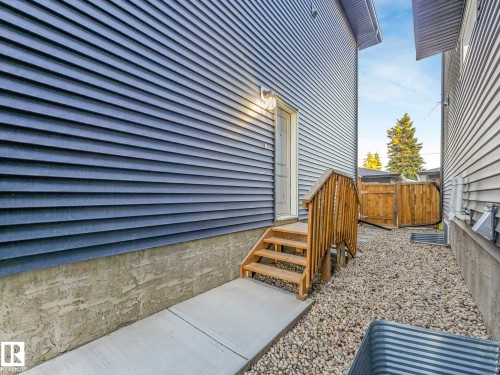 Side exterior entrance featuring wood-finish steps and handrail - 15731 109 Avenue, Edmonton, AB - Outdoor With Exterior