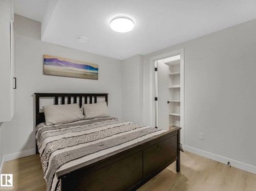 Bedroom featuring light wood-finish flooring, a flush-mount ceiling light, white baseboards, and a built-in closet with shelving - 15731 109 Avenue, Edmonton, AB - Indoor Photo Showing Bedroom